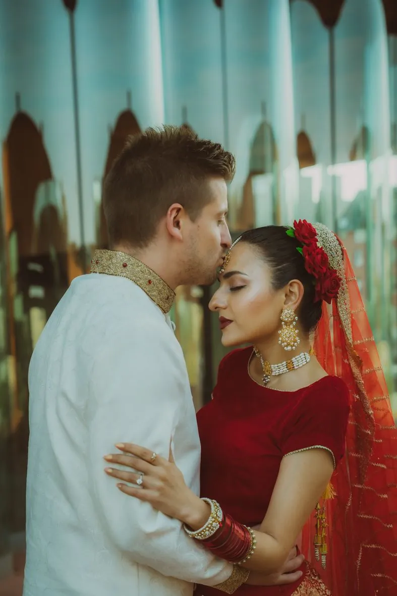 Portraits intimes du couple, mariée en tenue indienne rouge traditionnelle et marié en blanc