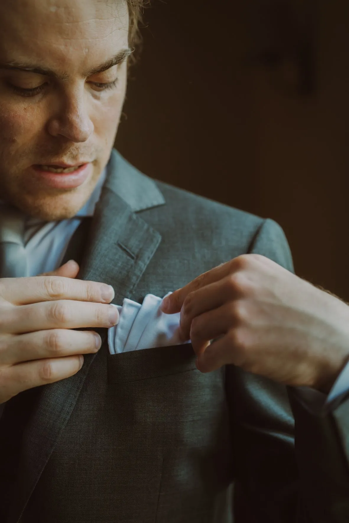 Gros plan de mains ajustant une tenue formelle dans une lumière d'ambiance