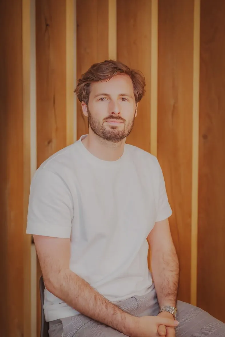 Personne en t-shirt blanc assise devant un treillis en bois dans une lumière chaude