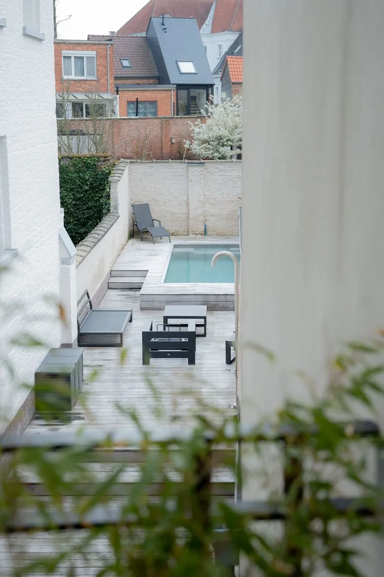 Vue sur jardin moderne avec piscine à travers des colonnes architecturales blanches