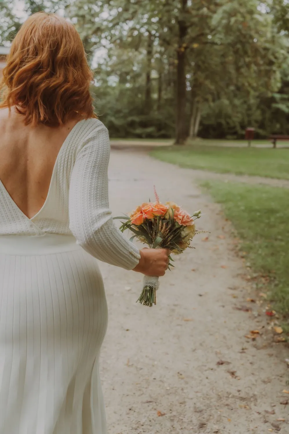 Mariée en robe blanche marchant avec un bouquet pêche