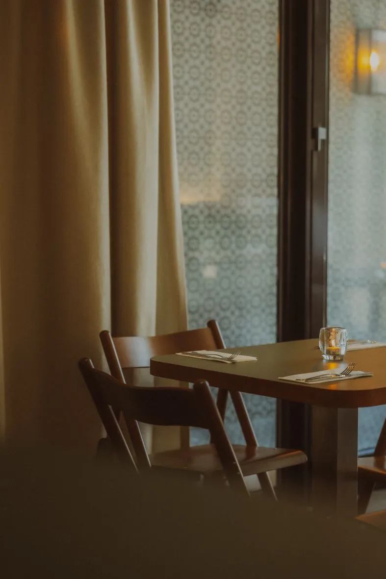 Intérieur chaleureux d'un restaurant avec chaises en bois et rideaux dorés