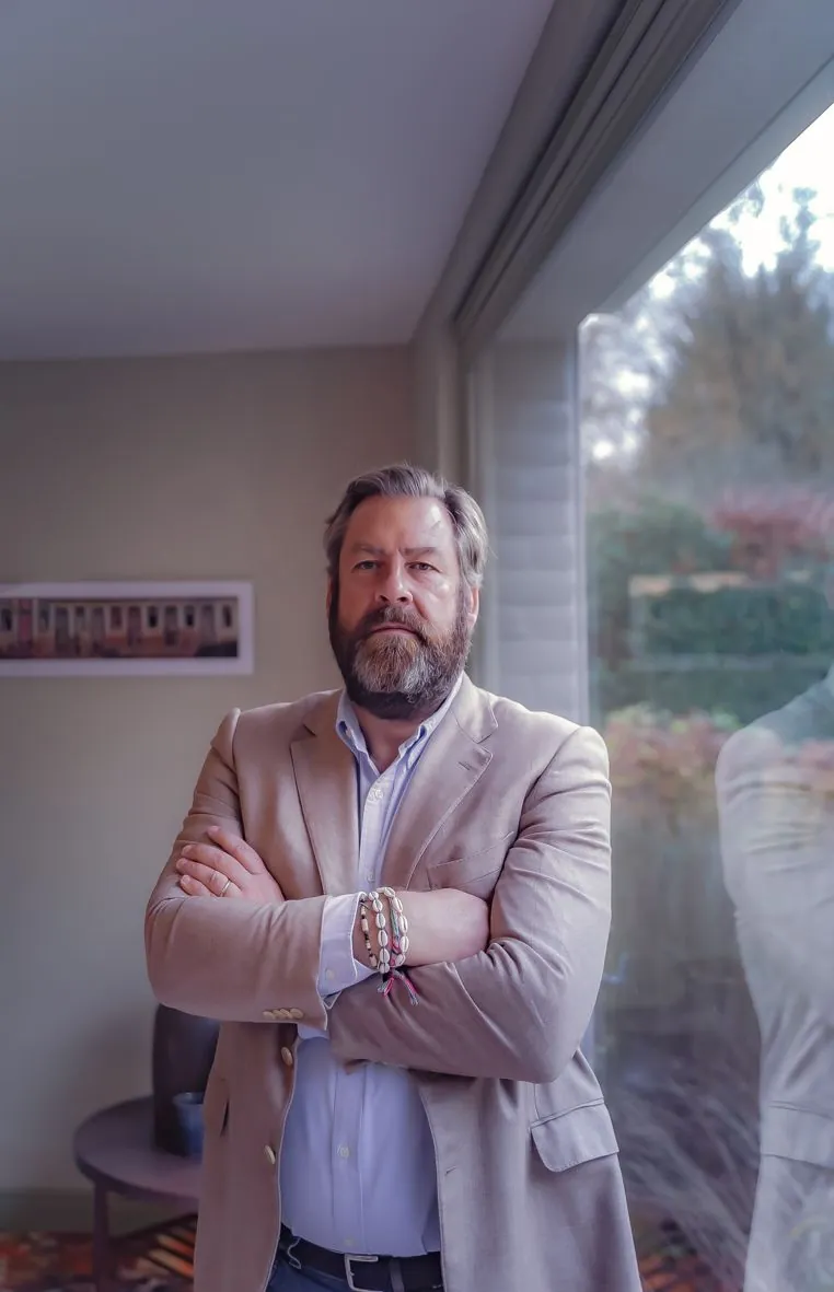 Professionnel en costume beige les bras croisés dans un bureau moderne