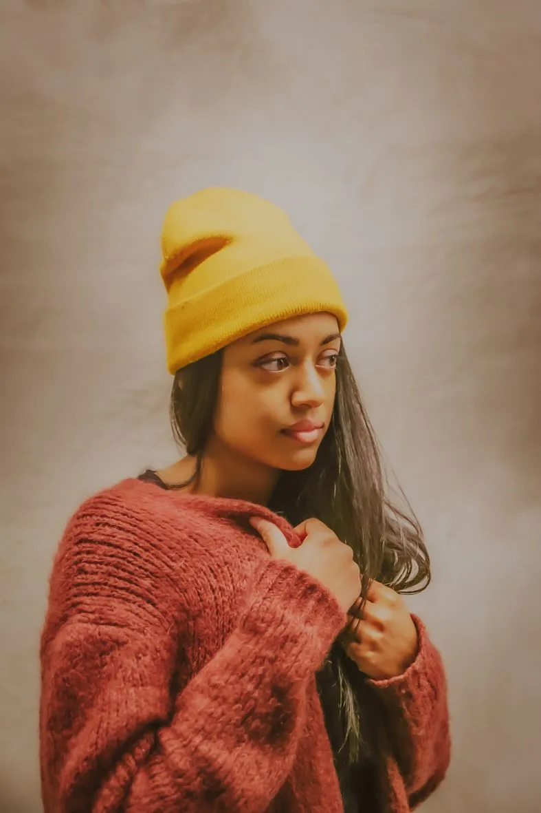Personne en bonnet jaune et pull rouge tricoté dans un portrait chaleureux