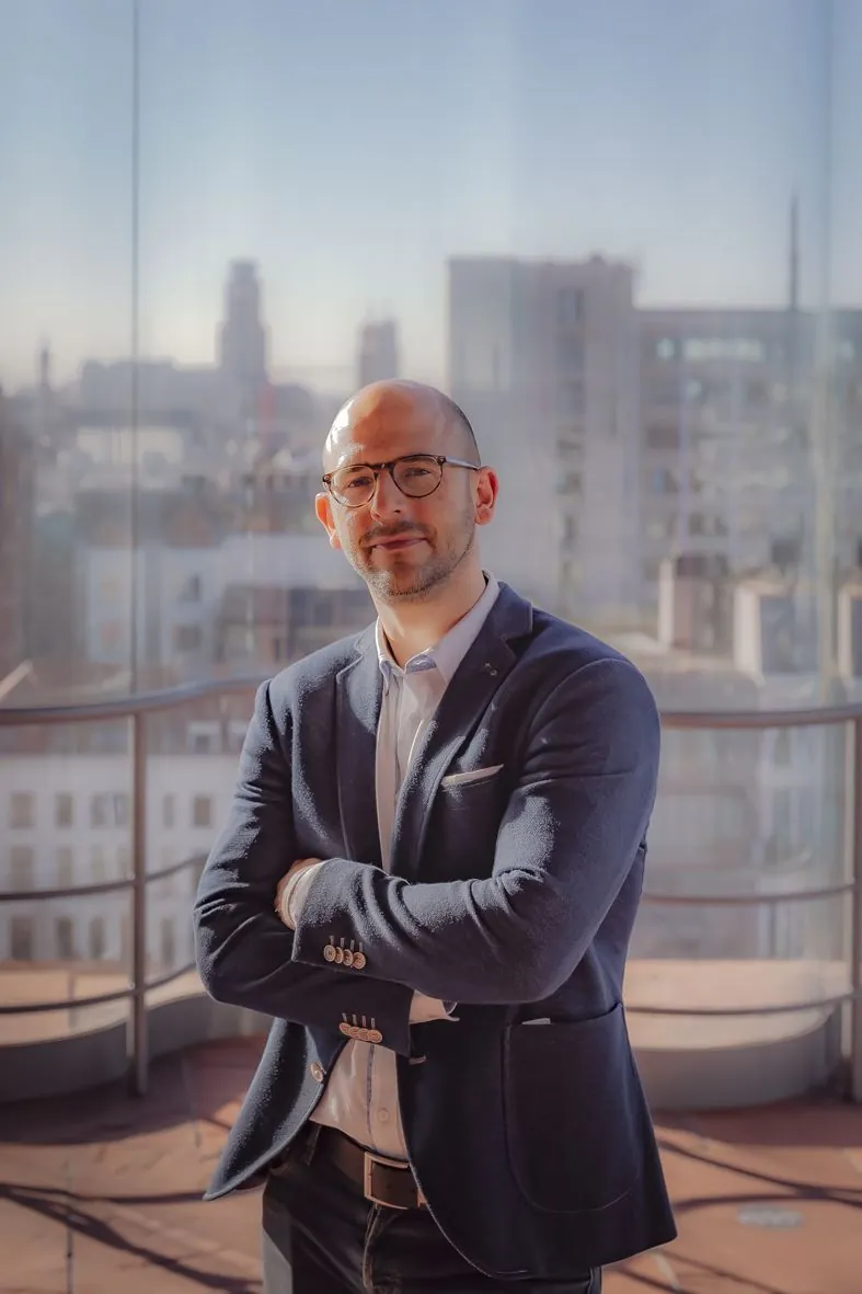 Portrait professionnel sur un rooftop urbain en costume sombre avec lunettes