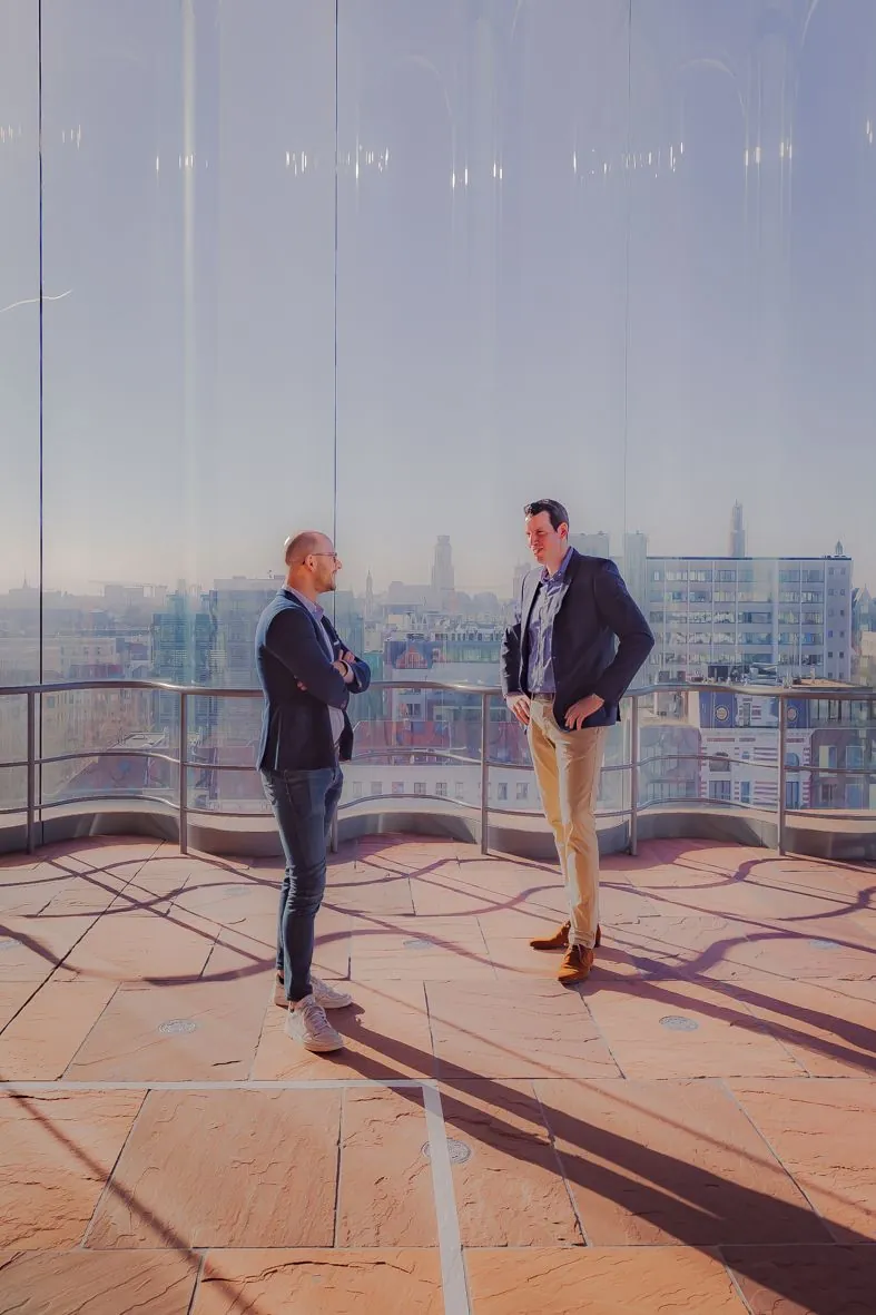 Deux personnes sur une terrasse ensoleillée avec paysage urbain